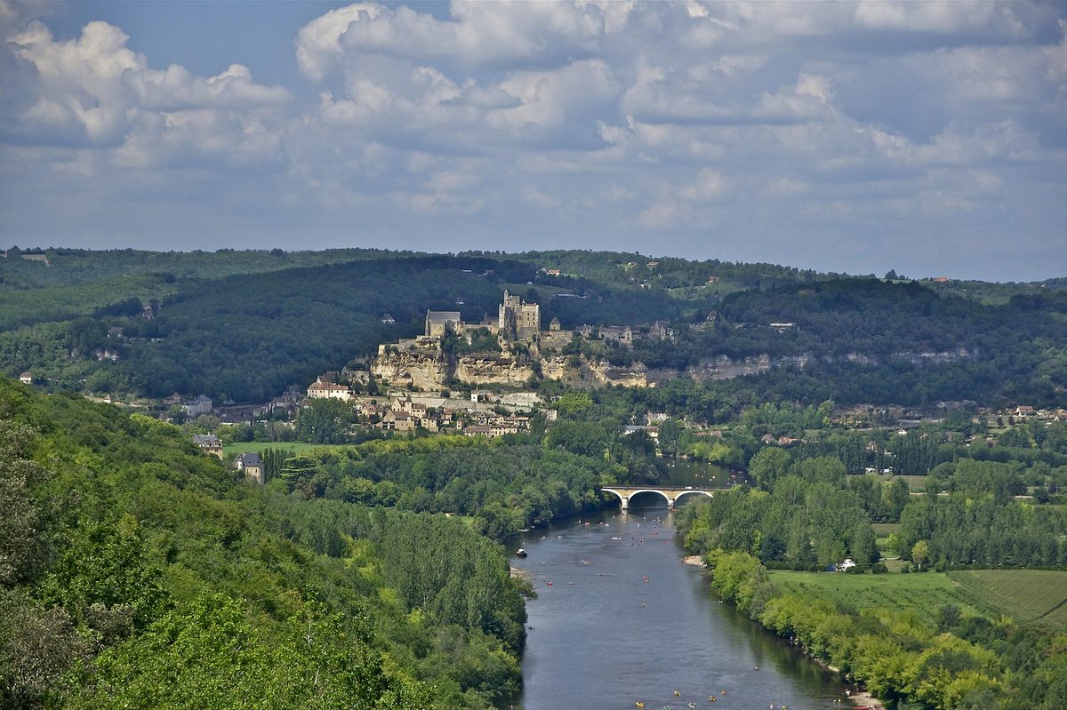 Beynac castle and village on a cliff above the Dordogne, seen from Castelnaud, with a bridge over the river