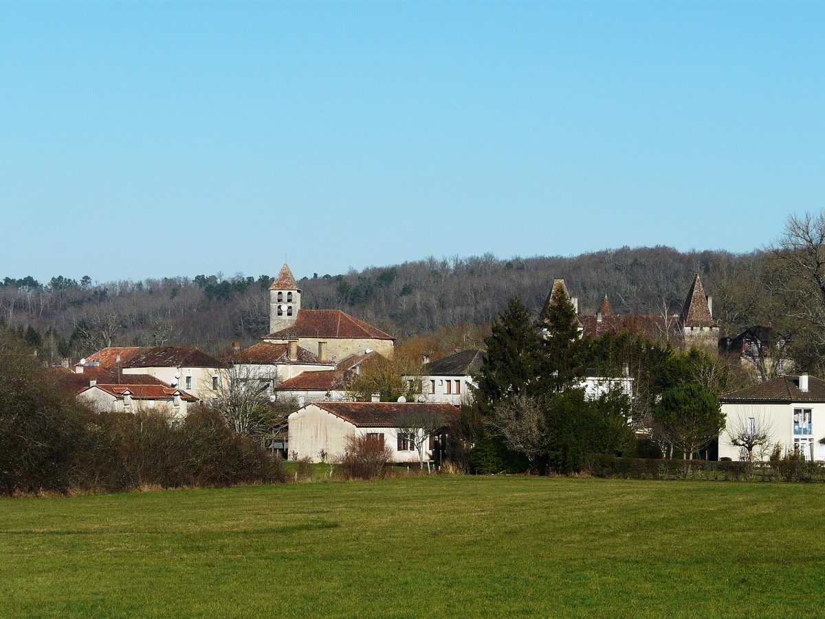 Saint-Jean-de-Côle: houses and the church tower beyond a green meadow